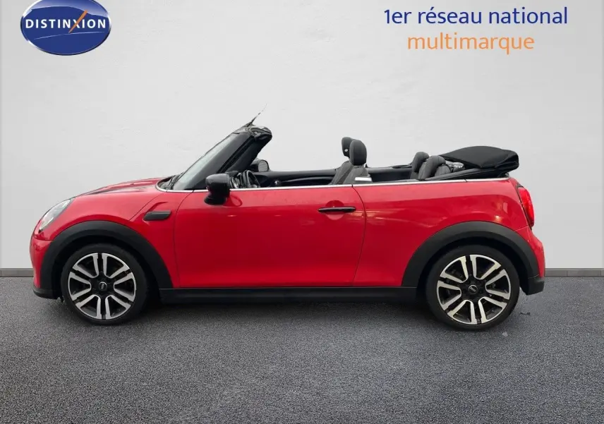 Vue de profil côté gauche d'une MINI Cabriolet rouge chili avec capote noire partiellement ouverte.