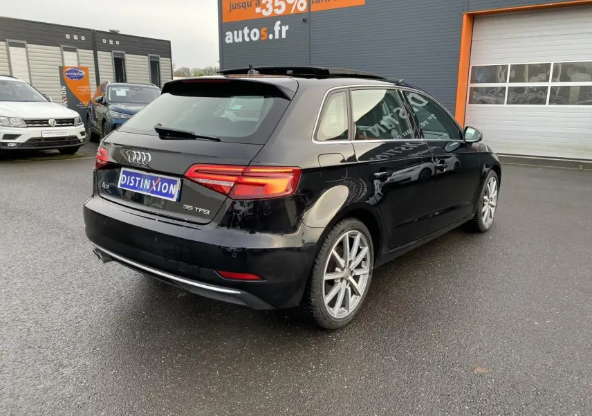 Audi A3 Sportback noire vue en 3/4 arrière droit, avec toit panoramique et jantes alliage visibles.