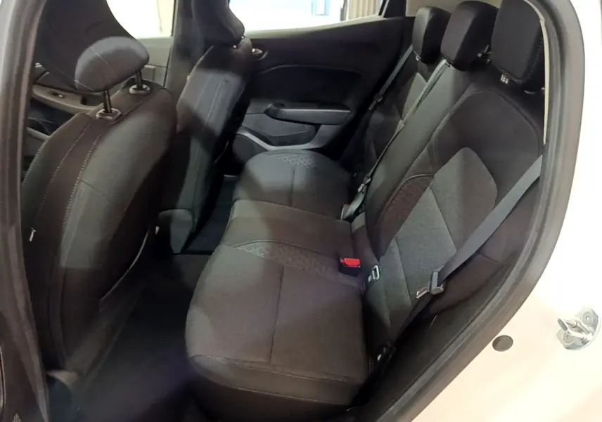 Vue intérieure arrière droite de la Renault Clio Business blanche, montrant la banquette 3 places en tissu noir.