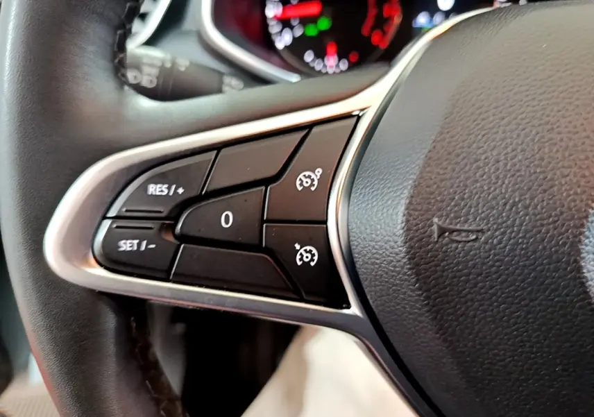 Gros plan sur les commandes de régulateur de vitesse au volant cuir noir de la Renault Clio Business blanche de 2021.