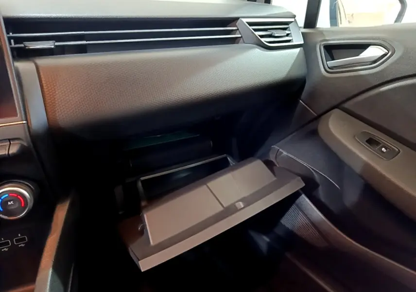 Intérieur de la Renault Clio Business blanc, vue côté passager avec boîte à gants ouverte et tableau de bord noir.