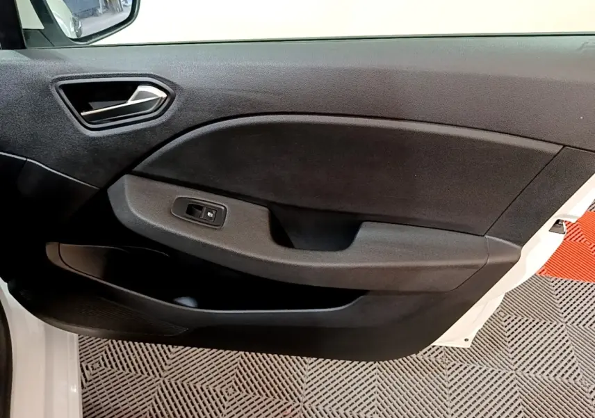 Vue rapprochée de la porte avant gauche noire intérieure d’une Renault Clio Business blanche, avec commande de vitre électrique.