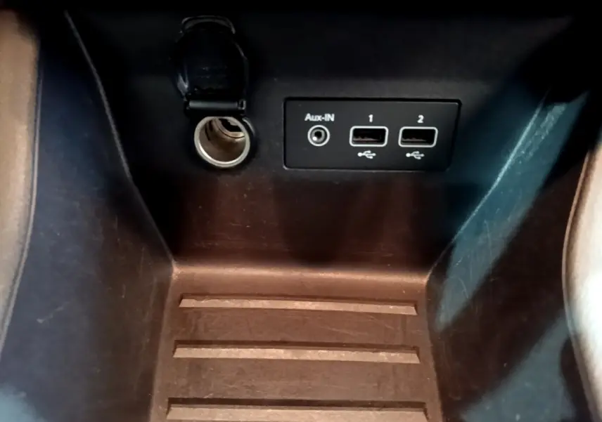 Gros plan sur la prise 12V, port Aux-IN et deux ports USB dans l’espace de rangement intérieur d’une Renault Clio blanche.