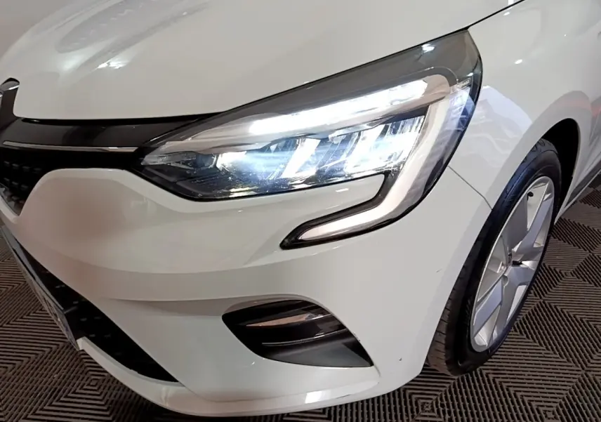 Gros plan sur l'avant droit blanc d'une Renault Clio Business 2021 avec phare LED allumé et jante visible.