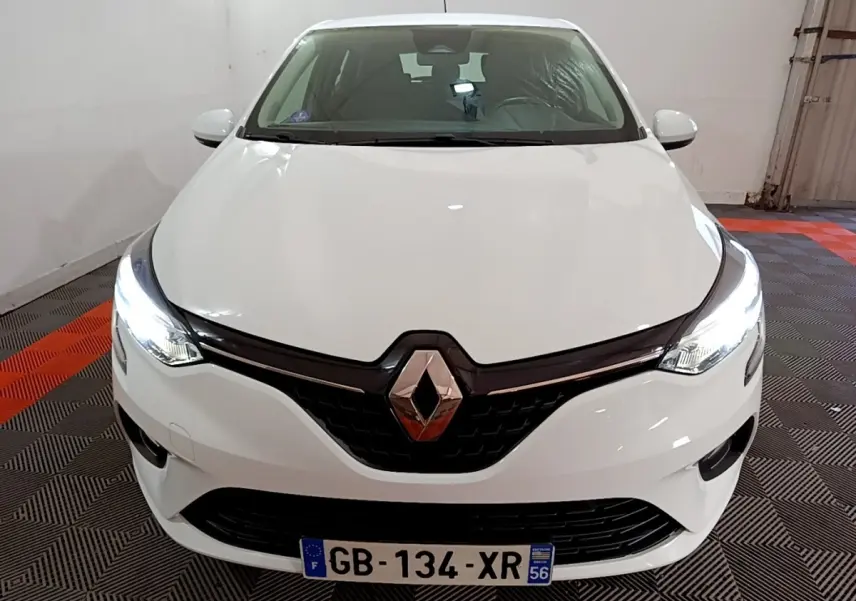 Vue de face d'une Renault Clio Business blanche avec phares LED allumés dans un garage.