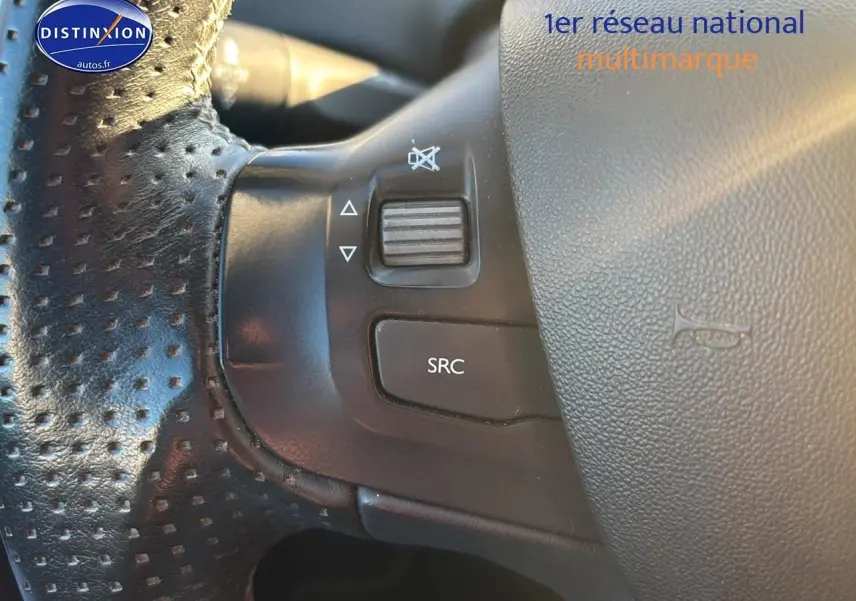Gros plan sur les commandes gauche du volant cuir perforé d’un Peugeot 2008 gris clair 2019.