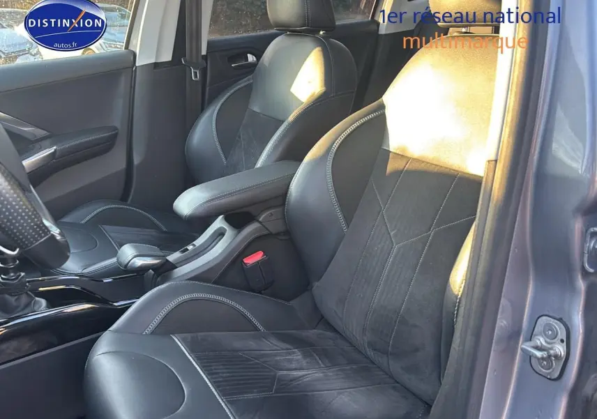 Vue intérieure côté conducteur de la Peugeot 2008 gris clair, sièges en cuir et alcantara noirs avec surpiqûres contrastantes.