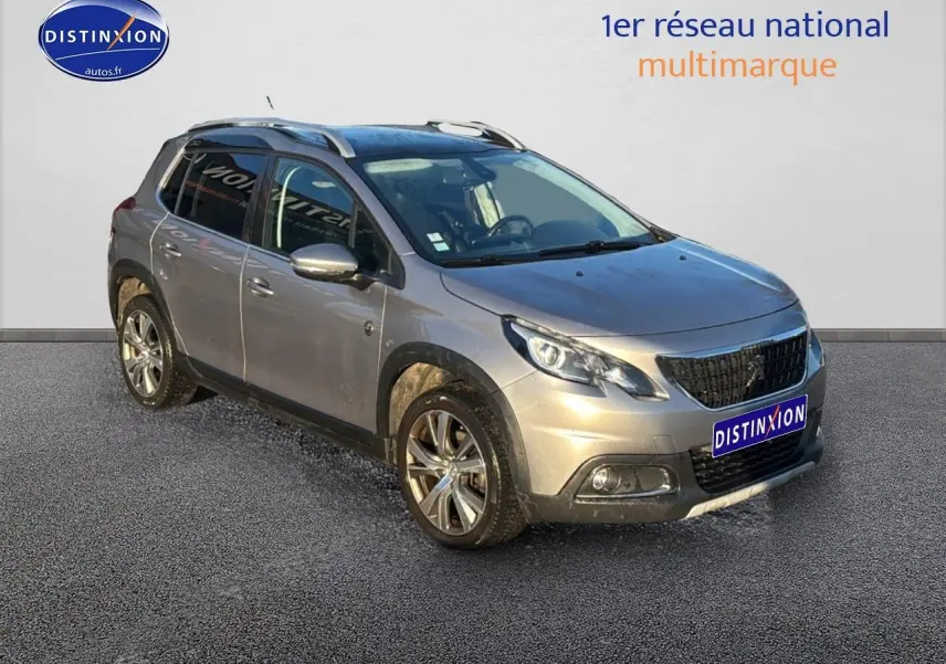 Peugeot 2008 gris clair en 3/4 avant droit avec barres de toit et jantes alu diamantées.