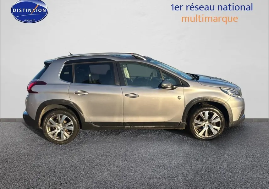 Vue de profil côté gauche d’un Peugeot 2008 gris clair avec barres de toit et jantes alliage.