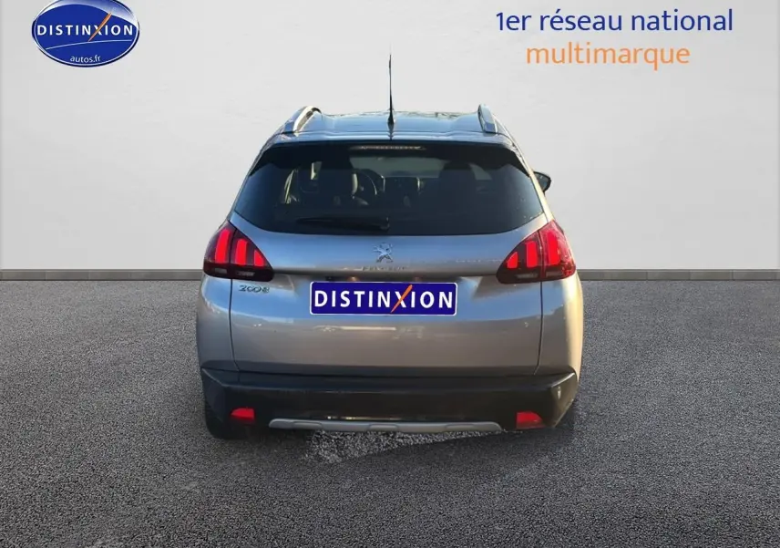 Vue arrière d'un Peugeot 2008 gris clair avec feux LED et barres de toit visibles sur fond neutre.