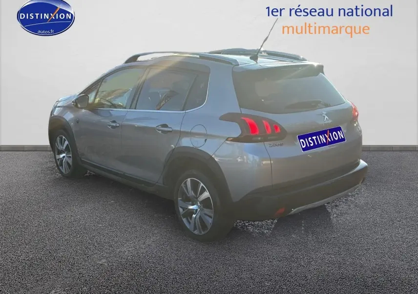 Peugeot 2008 gris clair vue 3/4 arrière droit, avec feux arrière LED et barres de toit visibles.
