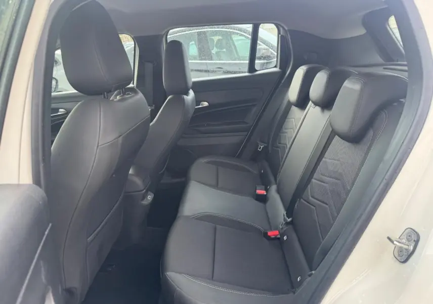 Vue intérieure côté gauche des sièges arrière noirs en tissu et cuir du Jeep Avenger blanc 2025, porte ouverte.