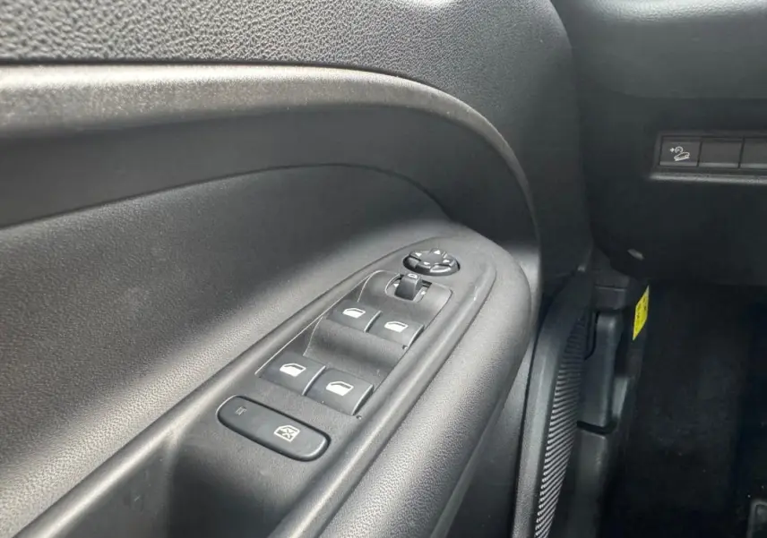 Gros plan sur le panneau de commandes des vitres électriques côté gauche intérieur du Jeep Avenger blanc 2025.
