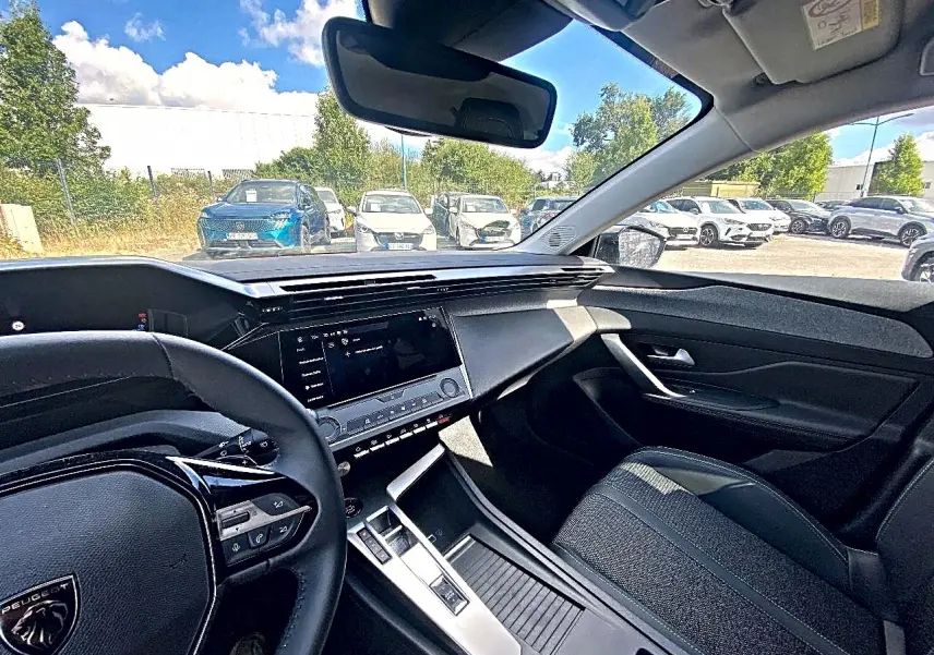 Vue intérieure côté conducteur de la Peugeot 308 gris 2025, avec tableau de bord moderne et écran tactile central.