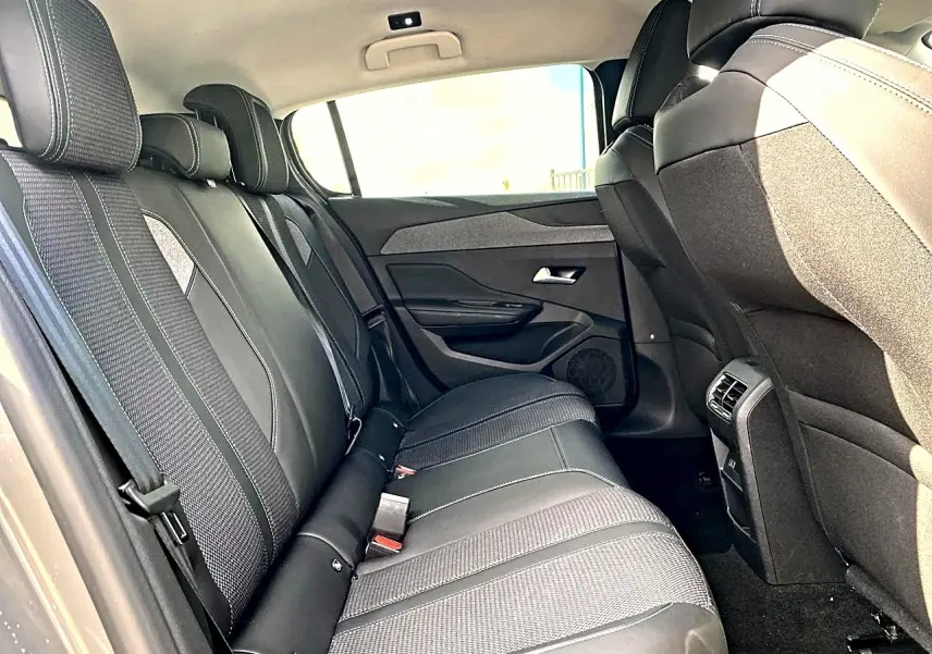 Vue intérieure côté droit sur la banquette arrière noire et grise de la Peugeot 308 2025, avec appuie-têtes et ceintures visibles.
