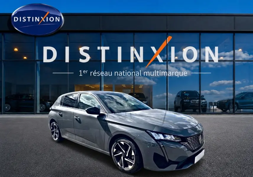 Peugeot 308 gris vue 3/4 avant droit, avec jantes alliage et calandre distinctive, devant showroom Distinxion.