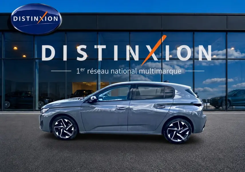Peugeot 308 gris vue de profil côté gauche, avec jantes alliage et vitres arrière surteintées devant un showroom Distinxion.