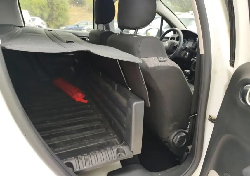 Vue intérieure côté droit du coffre utilitaire d'une Citroën C3 Société blanche, montrant l'espace de chargement et les sièges avant noirs.