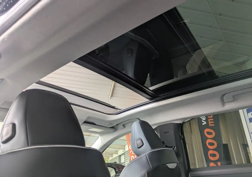 Vue intérieure du toit panoramique ouvert et des appuie-têtes en cuir noir du Citroën C5 Aircross hybride 2026.