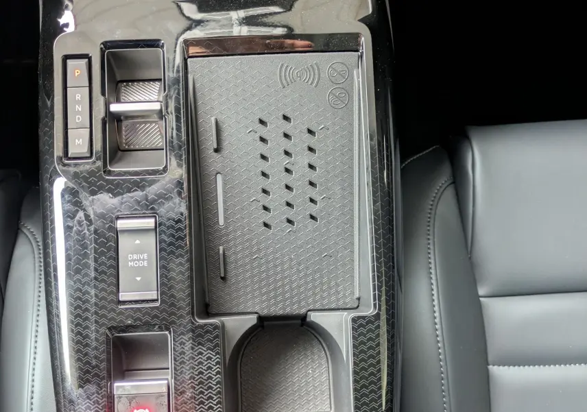 Vue plongeante sur la console centrale noire brillante du Citroën C5 Aircross hybride 2026 avec commandes et porte-gobelet.