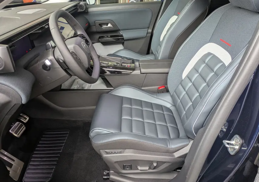 Vue intérieure côté conducteur du Citroën C5 Aircross hybride 2026, sièges en cuir bleu avec surpiqûres et console centrale noire brillante.