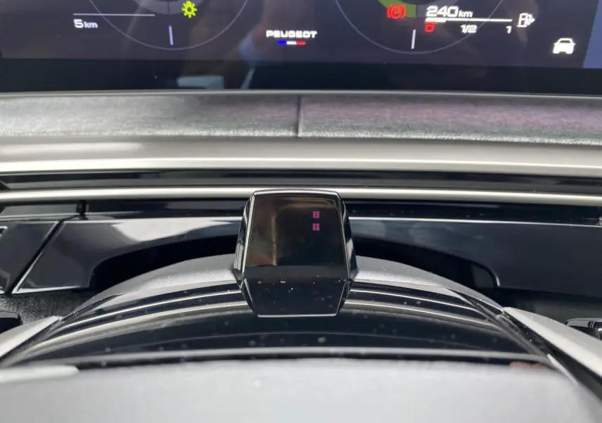 Vue rapprochée du tableau de bord numérique et du volant du Peugeot 3008 hybride, affichage digital et logo Peugeot visible.
