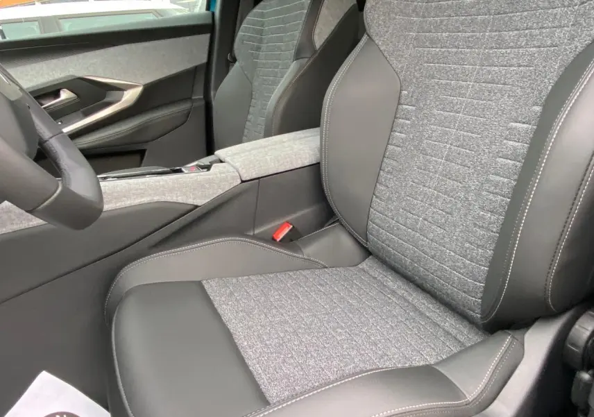 Vue intérieure rapprochée du siège avant droit gris et noir du Peugeot 3008 Hybrid 2026 avec accoudoir central tissu.
