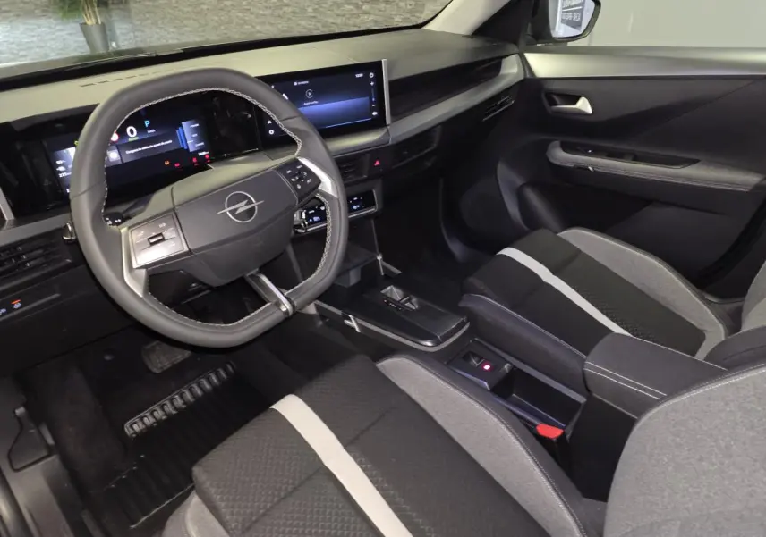 Vue intérieure côté conducteur de l'Opel Frontera-e 2025, avec tableau de bord numérique et sellerie tissu gris et noir.