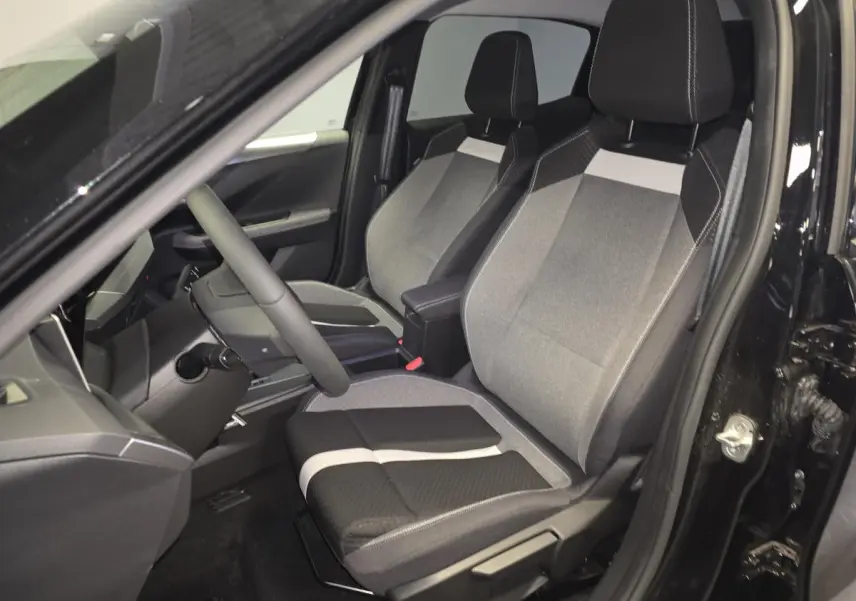 Vue intérieure côté conducteur de l'Opel Frontera-e 2025 noire, sièges tissu bicolore gris et noir avec accoudoir central.