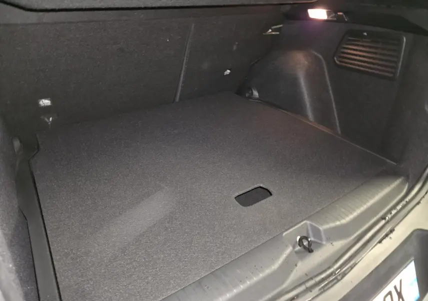 Coffre spacieux de l’Opel Frontera-e 2025 noir, vue intérieure arrière avec plancher modulable et éclairage intégré.