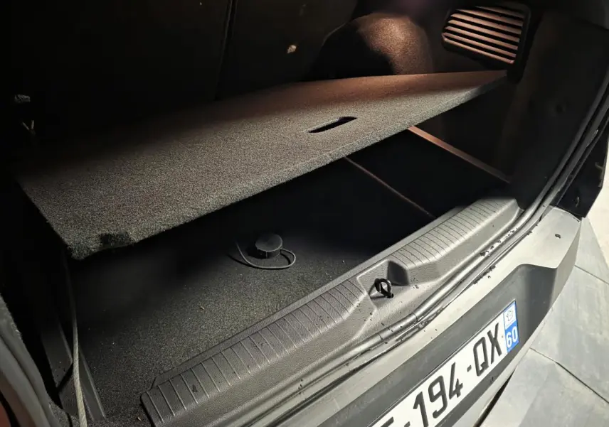 Coffre ouvert en vue rapprochée d’un Opel Frontera-e noir, montrant le plancher modulable et la plaque d’immatriculation arrière.
