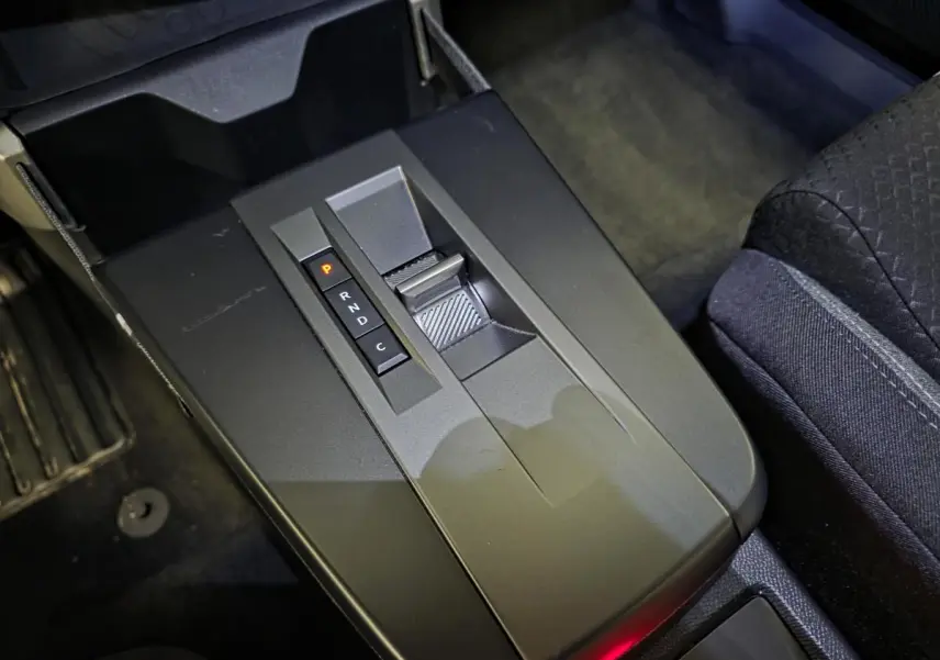 Gros plan sur la console centrale noire de l'Opel Frontera-e 2025 avec levier de boîte automatique et sièges tissu noirs.