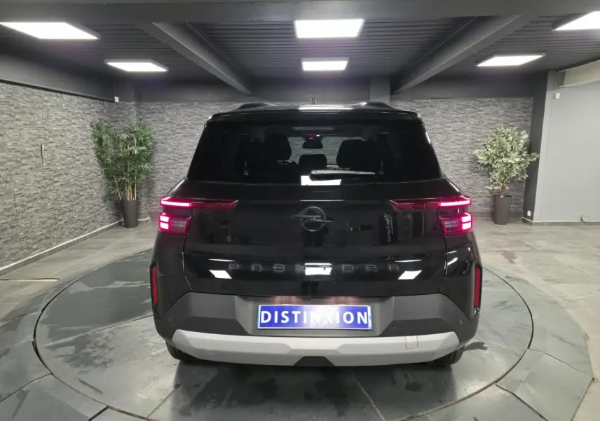Vue arrière d'un Opel Frontera-e noir métallisé, avec feux LED allumés et logo Opel visible, en intérieur showroom.