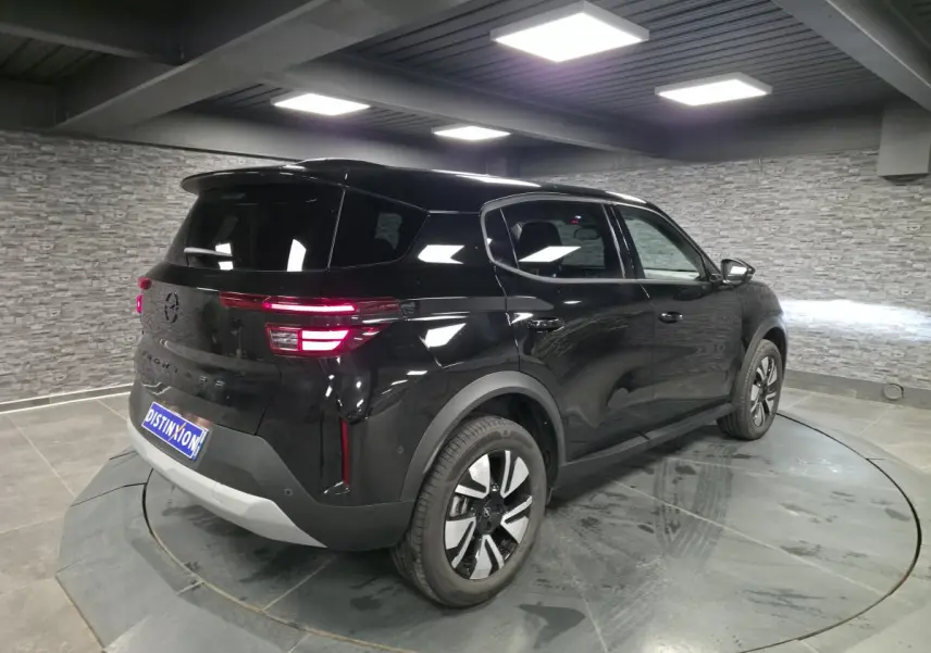 Opel Frontera-e noire vue 3/4 arrière droit, avec jantes alliage 17'' et toit noir Karbon en intérieur showroom.