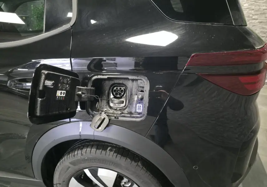 Vue arrière côté gauche d'une Opel Frontera-e noire avec trappe de recharge électrique ouverte et jante alliage 17 pouces.