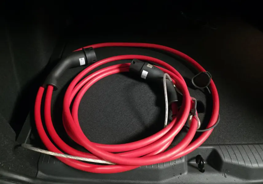 Câble de recharge électrique rouge enroulé dans le coffre d’un Opel Frontera-e noir, vue intérieure arrière.