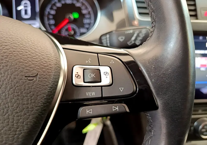 Gros plan sur les commandes multifonctions du volant cuir noir d'une Volkswagen Golf 1.6 TDI 2019.