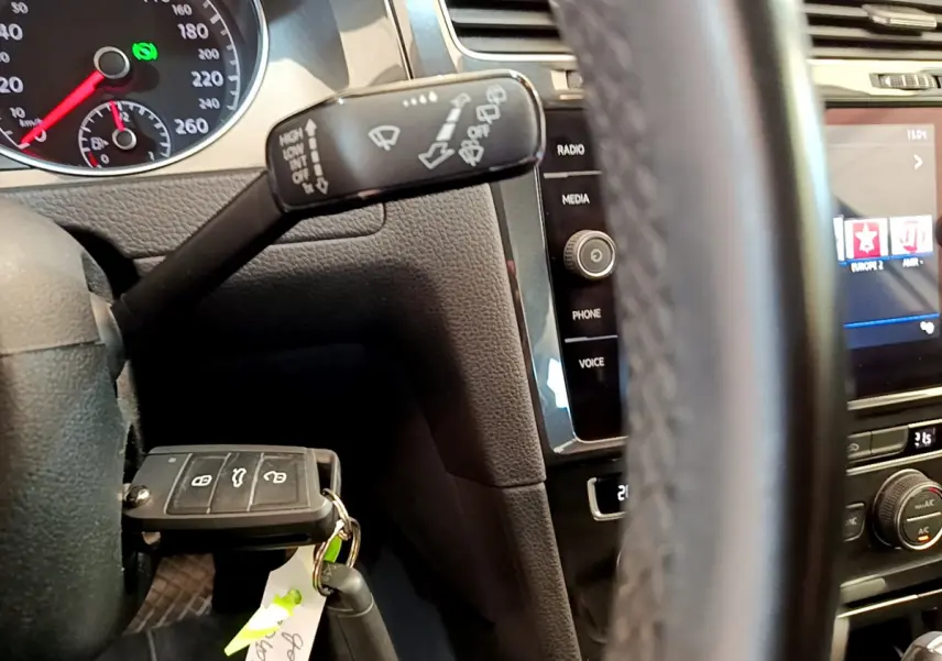 Gros plan sur le volant et tableau de bord noir d'une Volkswagen Golf 2019, avec clé insérée et commandes multimédia visibles.