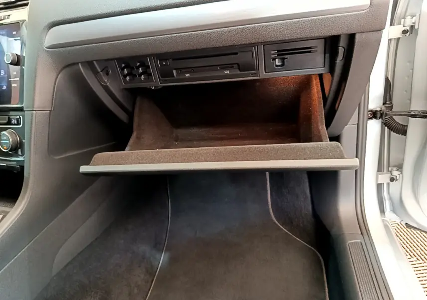 Gros plan sur la boîte à gants ouverte du Volkswagen Golf gris clair 2019, montrant les lecteurs SD et l'éclairage intérieur.