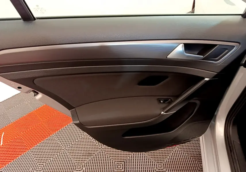 Vue intérieure côté gauche de la porte avant grise de la Volkswagen Golf 2019 avec garniture noire et insert bois.