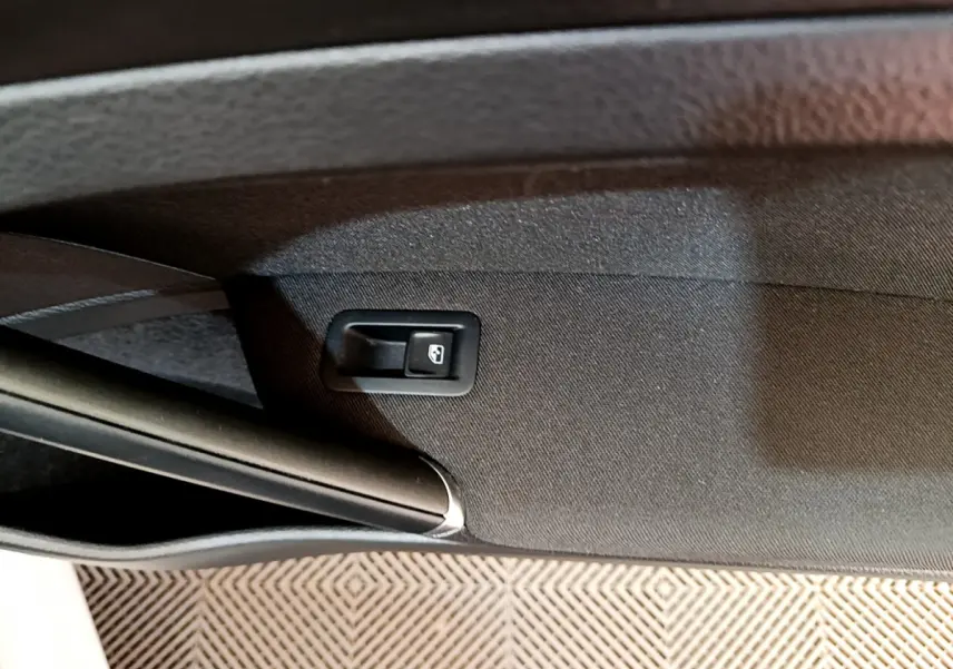 Détail de la commande d'ouverture de coffre sur la garniture intérieure noire d'une Volkswagen Golf gris clair 2019.