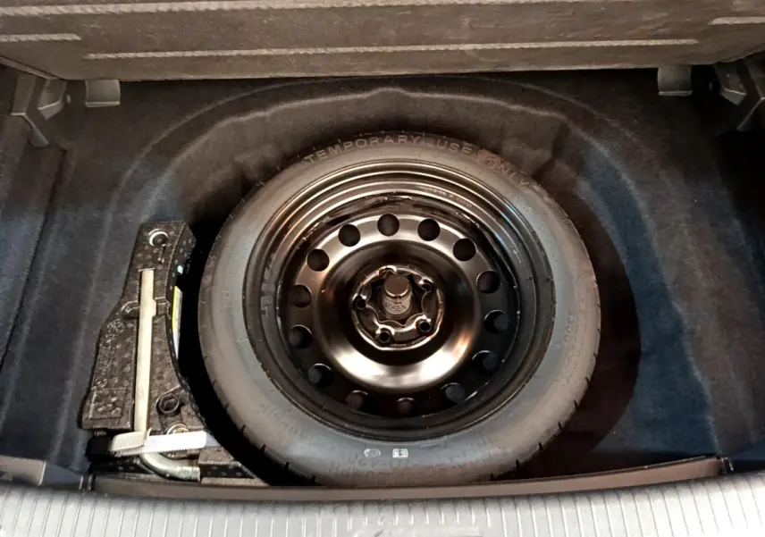 Roue de secours galette noire dans le coffre d'une Volkswagen Golf 1.6 TDI 2019 gris clair.