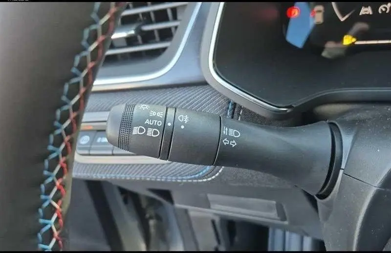 Gros plan sur la commande des feux et clignotants du Renault Captur E-Tech hybride, intérieur noir avec surpiqûres tricolores.