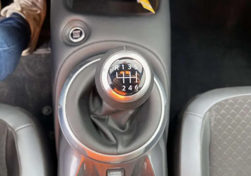 Le levier de vitesses manuel du Nissan Juke 2024 en gros plan, entouré de sièges gris.