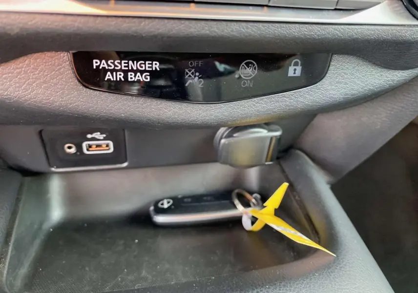 Gros plan sur la console centrale du Nissan Juke 2024 blanc perle, avec clé et ports USB visibles.