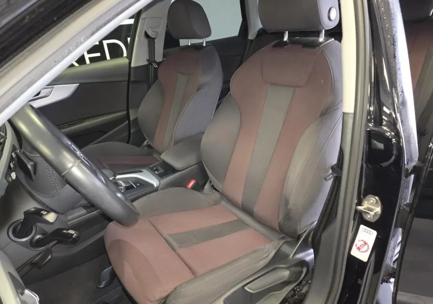 Vue intérieure côté conducteur de l'Audi A4 Avant noire, mettant en valeur les sièges sport bicolores et la console centrale.