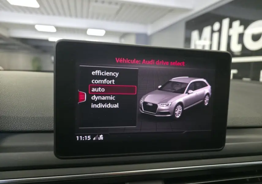 Écran intérieur montrant l'Audi A4 Avant en gris clair avec sélection du mode de conduite auto sur l'interface.