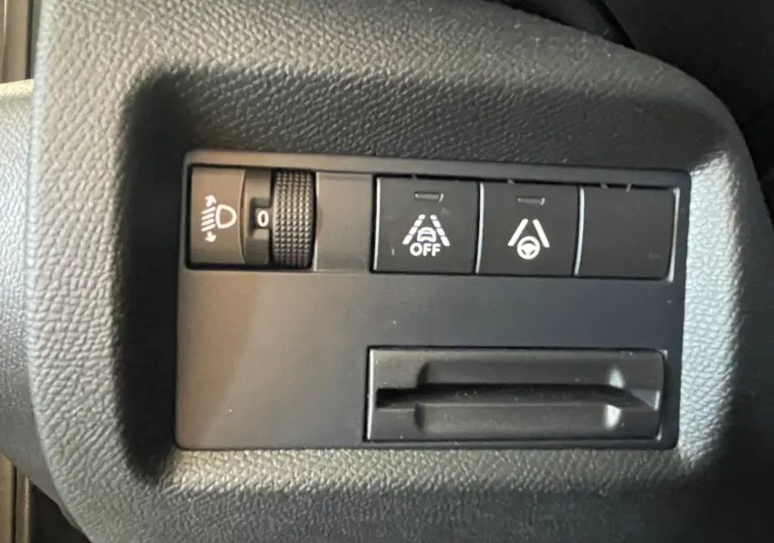 Panneau de commandes intérieures noires du Citroën C5 Aircross hybride, avec boutons de réglage des phares et aides à la conduite.