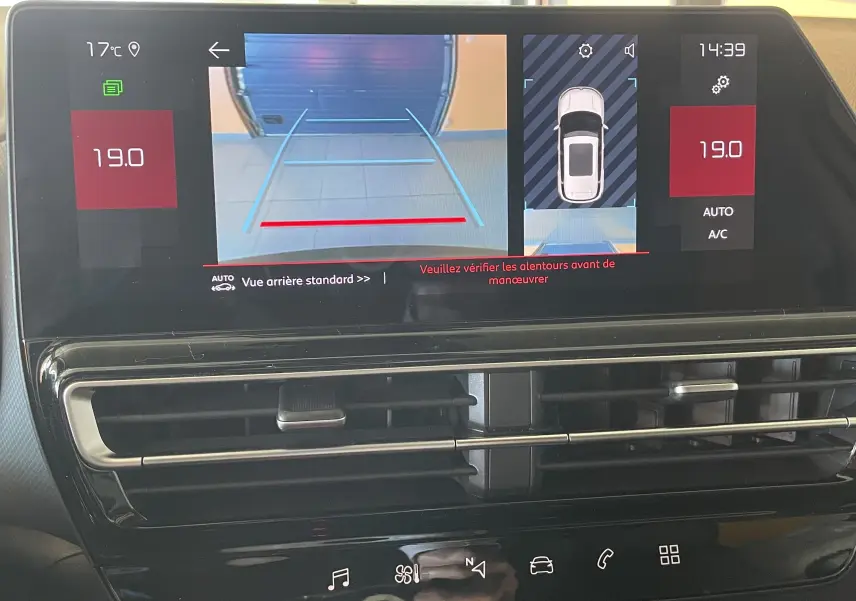 Écran central du tableau de bord du Citroën C5 Aircross hybride 2025 montrant la caméra de recul et l'affichage de la climatisation.