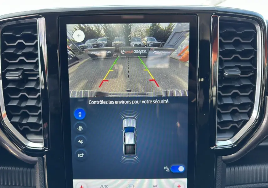 Vue rapprochée de l'écran central du Ford Ranger gris carbone montrant la caméra de recul et les capteurs de stationnement.